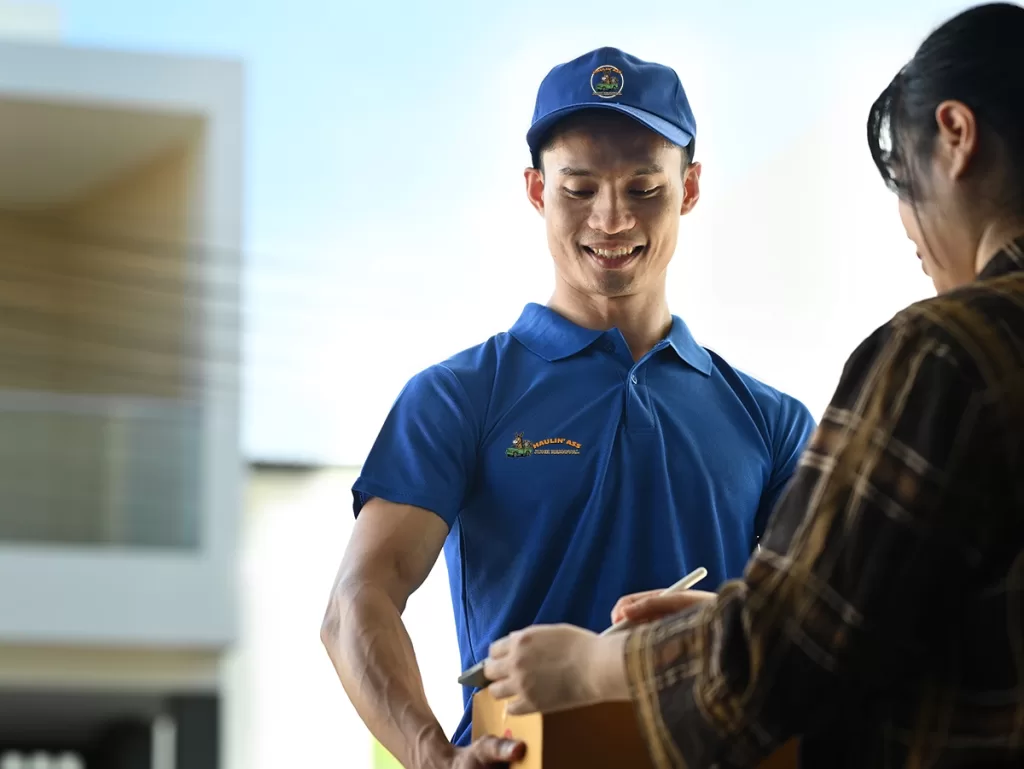 Haulin’ Ass Junk Removal delivery worker getting a signature from a homeowner at the front door