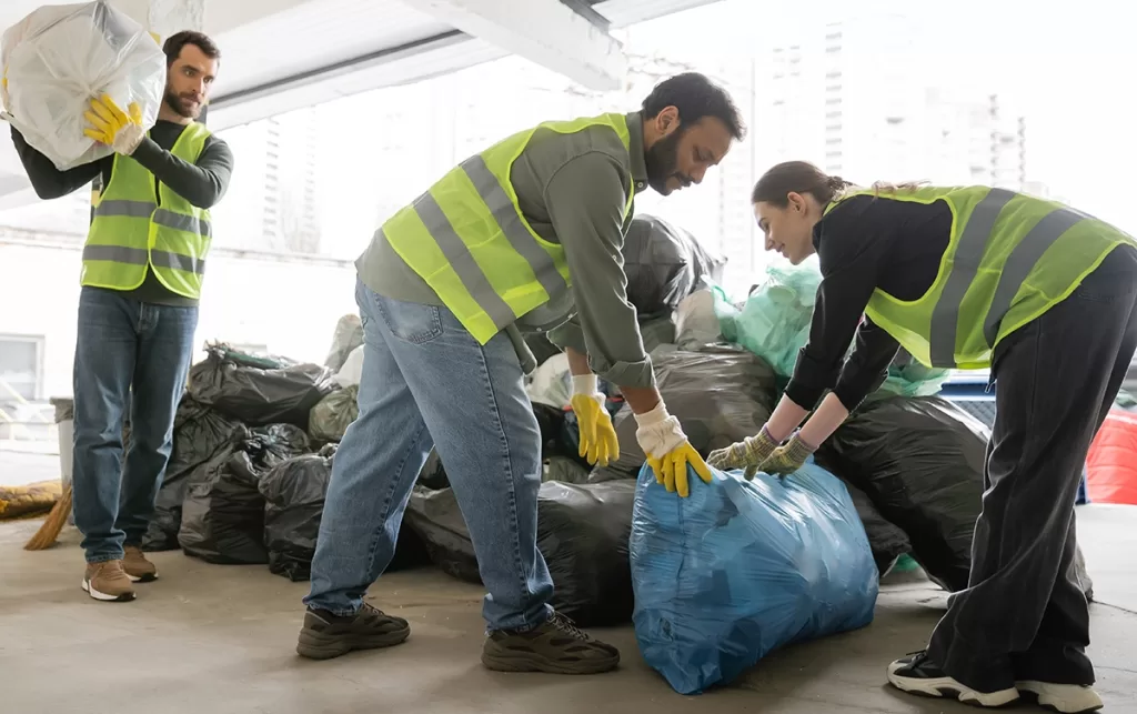 Workers loading yard debris and construction waste into a dump truck