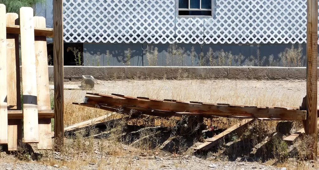 Broken fence panels and deck boards lying on the ground ready for removal