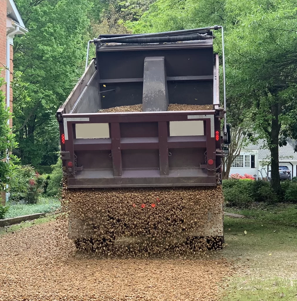 Haulin’ Ass truck delivering and spreading new gravel on a residential driveway