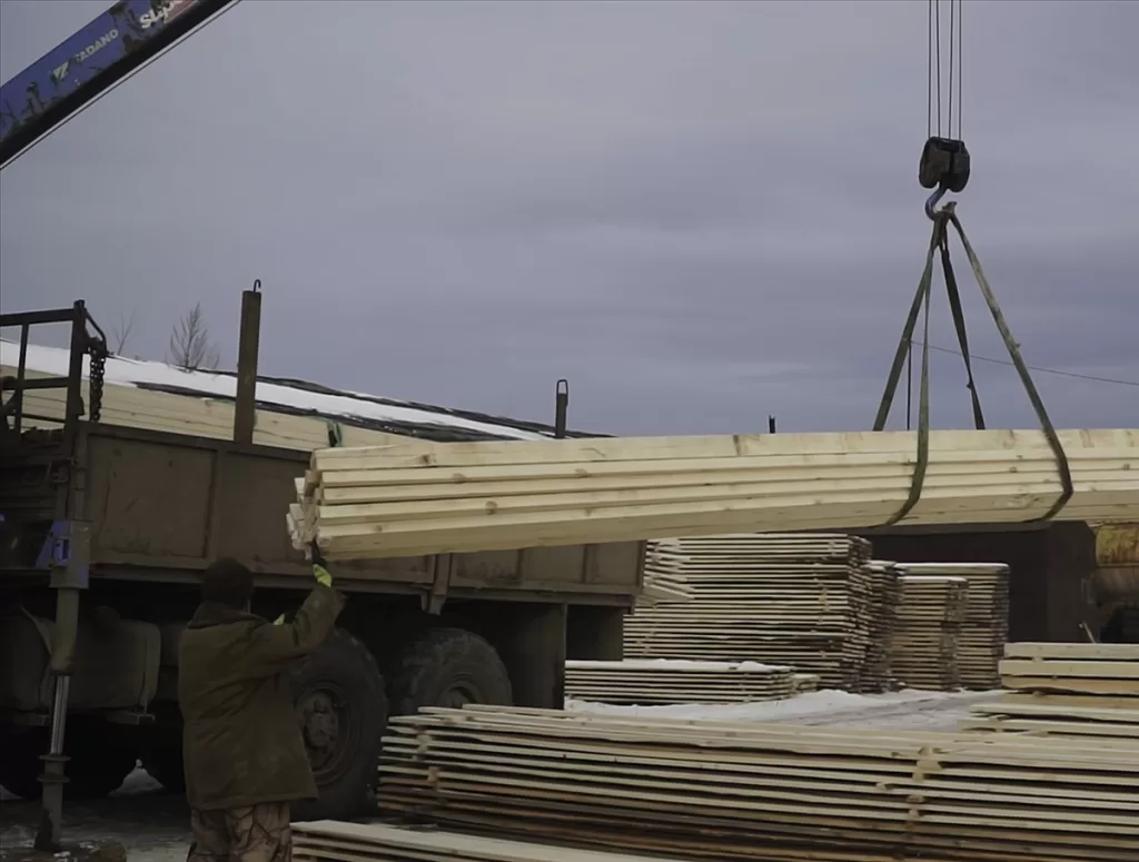Wooden planks being lifted by a crane for safe vehicle delivery from haulin' ass services